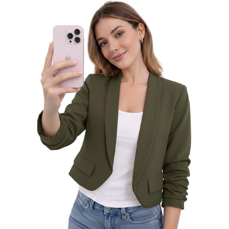 Woman taking a selfie wearing an olive green blazer over a white top and blue jeans on a white background