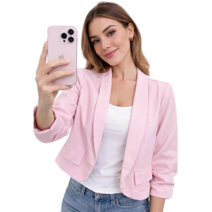 Woman wearing a pink blazer over a white top and blue jeans, holding a pink phone.