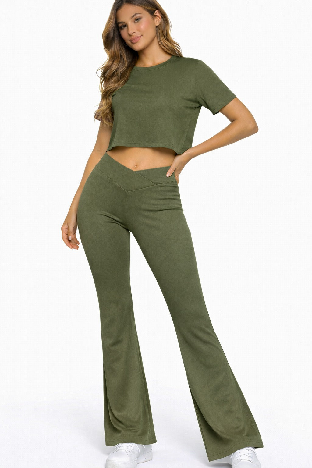 Woman wearing an olive green outfit with a crop top and flared pants on a white background