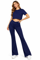 Woman wearing a navy blue outfit with a matching top and pants on a white background
