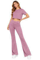 Woman wearing a matching purple top and flared pants set on a white background
