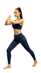 Woman wearing a navy blue sports bra and leggings on a white background