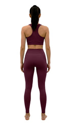 Person wearing a maroon sports bra and leggings set on a white background