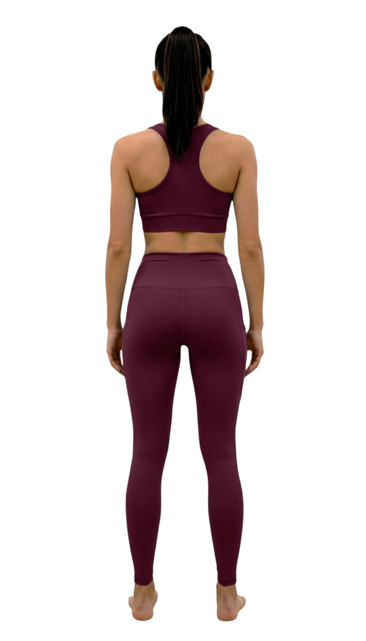 Person wearing a maroon sports bra and leggings set on a white background