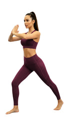 Woman wearing a purple athletic outfit posing on a white background