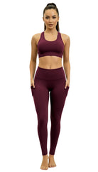 Woman wearing a maroon sports bra and leggings set on a white background